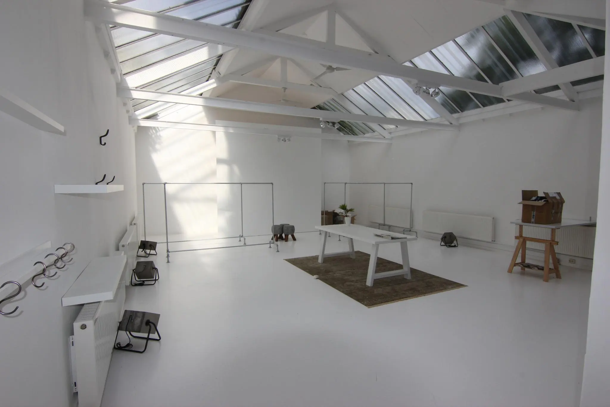 Lichte, minimalistische werkruimte met witte muren, glazen dak en moderne meubels aan de Graaf Florisstraat.